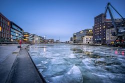 Der gefrorene Stadthafen von Münster bei Dämmerung, mit dem historischen Hafen-Kran und modernen Gebäuden im Hintergrund, fotografiert von Sascha Talke.