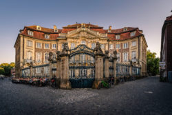 Der historische Erbdrostenhof in der Altstadt von Münster, belebt durch ein Straßencafé und umgeben von Fahrrädern, festgehalten im warmen Abendlicht.