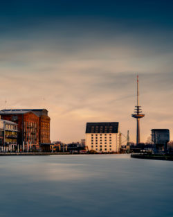 Abenddämmerung am Stadthafen Münster mit Fernmeldeturm und Getreidespeicher, friedliche Reflexion im Wasser.