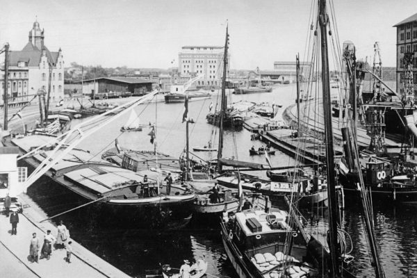 Historisches Schwarz-Weiß-Foto des Stadthafens in Münster mit mehreren Segelbooten und geschäftigen Menschen am Ufer.