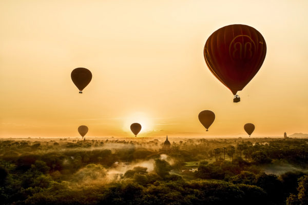 Heißluftballons schweben lautlos im goldenen Sonnenaufgang, fotografiert von Annemarie Berlin.