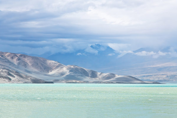 Sandberge mit Schneekappen unter bewölktem Himmel an einem türkisfarbenen Gewässer - © Annemarie Berlin