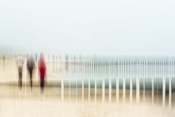 Ein künstlerischer, verschwommener Strandspaziergang mit pastellfarbenen Tönen und abstrakten Figuren, fotografiert von Annemarie Berlin.