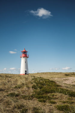 Leuchtturm "List-West" auf Sylt, umgeben von Dünen und Gras, unter einem weiten, blauen Himmel, Fotografin: Beate Zoellner.