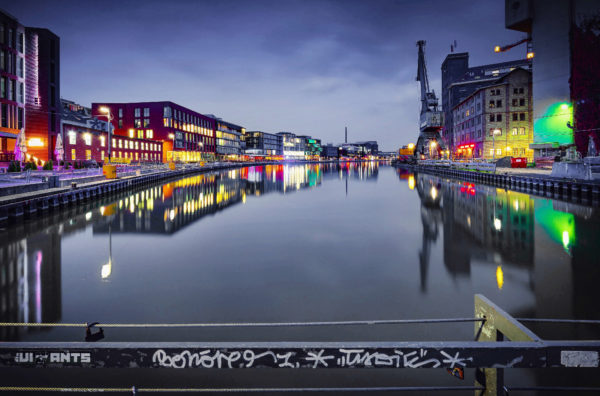 Der Stadthafen von Münster bei Nacht, mit dem Hafenkran und dem Wolfgang Borchert Theater im Hintergrund, fotografiert von Thomas Branse.