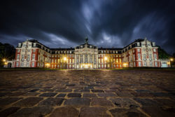 Nachtaufnahme des Fürstbischöflichen Schlosses Münster mit dramatischem Himmel und beleuchtetem Schlossgebäude.