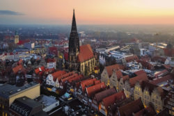 Atemberaubende Luftaufnahme von Münster mit St. Lamberti-Kirche, Altstadt und Prinzipalmarkt bei Sonnenaufgang und einem beleuchteten Weihnachtsbaum.