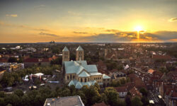 Verzaubernder Sonnenuntergang über der historischen Altstadt von Münster mit St.-Paulus-Dom und Liebfrauen-Überwasserkirche im Hintergrund.