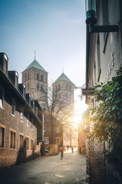 St.-Paulus-Dom Türme durch eine sonnige Kopfsteinpflastergasse in Münster fotografiert von Sascha Talke