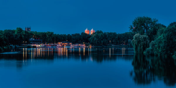 Aasee bei Nacht mit beleuchtetem Dom und Liebfrauen-Überwasserkirche, umgeben von Bäumen