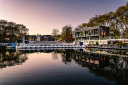 Bild der Aaseeterassen in Münster bei Sonnenuntergang mit Tretbooten am Pier und lila-rotem Himmel