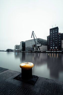 Langzeitbelichtung des Stadthafen Münster, mit dem Hafen-Kran und der Hafenkäserei unter einem grauen Himmel.