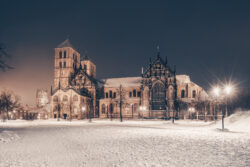 Verschneiter Domplatz in Münster mit St.-Paulus-Dom im Hintergrund bei Nacht.