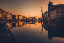 Sonnenuntergang über dem Stadthafen Münster, mit spiegelnden Gebäuden und dem Hafen-Kran im ruhigen Kanal.